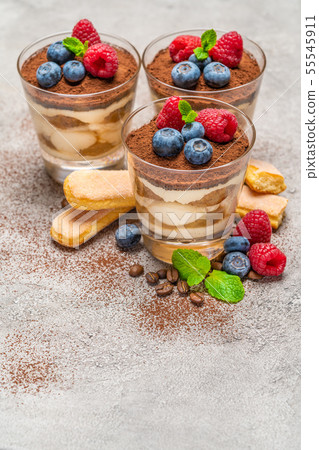 Classic tiramisu dessert with blueberries and raspberries and savoiardi cookies in a glass on Classic tiramisu dessert with blueberries and raspberries and savoiardi cookies in a glass on 55545911