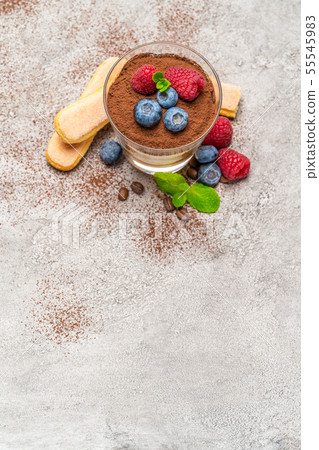 Classic tiramisu dessert with blueberries and raspberries and savoiardi cookies in a glass on Classic tiramisu dessert with blueberries and raspberries and savoiardi cookies in a glass on 55545983