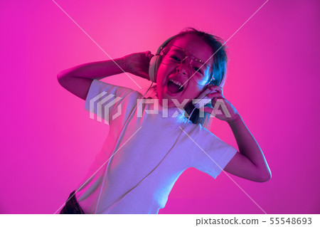 Portrait of little girl in headphones on purple gradient background in neon light Portrait of little girl in headphones on purple gradient background in neon light 55548693