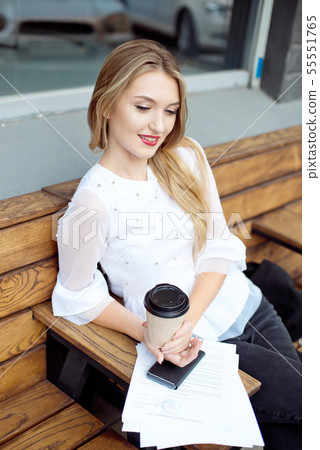 Businesswoman reading paper in cafe during lunch break. Business woman reads and underlines notes in 55551765