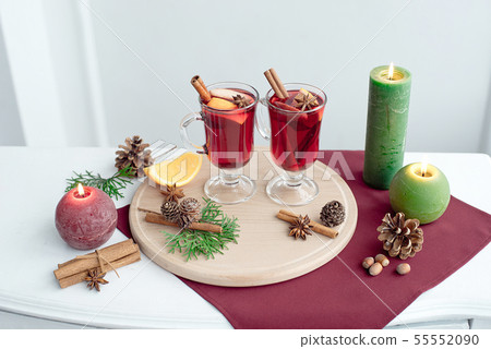 Two glasses of mulled wine with cinnamon sticks, a dry slice of oranges and cones, star anise on a Two glasses of mulled wine with cinnamon sticks, a dry slice of oranges and cones, star anise on a 55552090