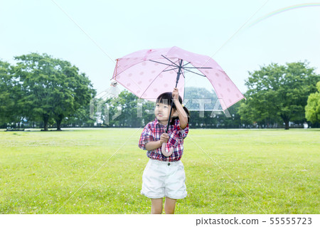 A little girl staring at the tertel shaven with an umbrella in the rainy park. 55555723