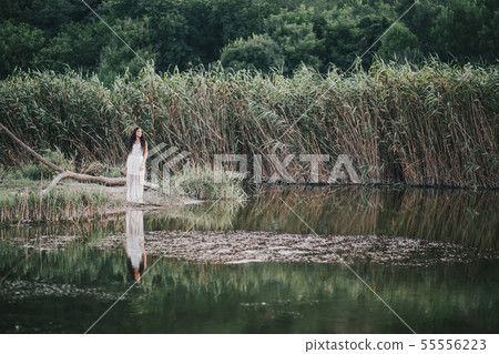 Woman in boho dress posing near lake. 55556223