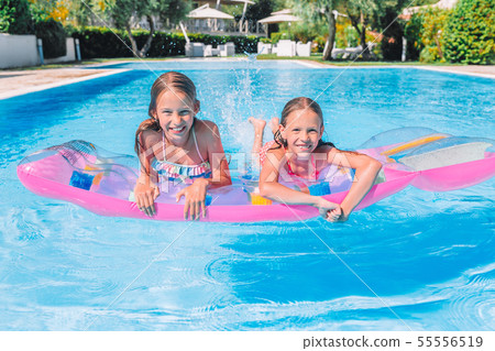 Adorable little sisters play in outdoor swimming pool 55556519