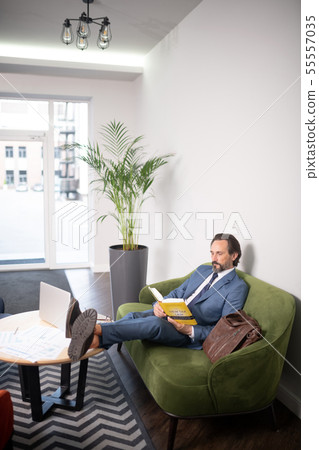 Businessman putting legs on table reading book having little break 55557035