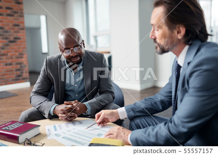 Dark-skinned man speaking with his lawyer sitting in the office Dark-skinned man speaking with his lawyer sitting in the office 55557157