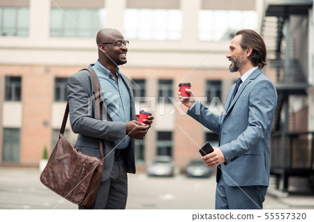 Bearded businessman speaking with colleague and drinking coffee 55557320