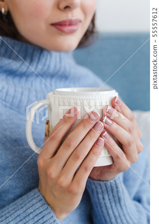 close-up of a girl in a blue sweater with a cup of hot tea in her hands close-up of a girl in a blue sweater with a cup of hot tea in her hands 55557612