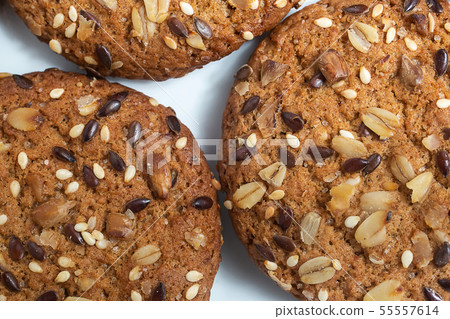 Macro photo of brown dietary low-calorie fitness cereal biscuits with sprinkling closeup on white 55557614