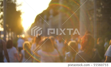 Unknown young people walk along the street at sunset Unknown young people walk along the street at sunset 55560733