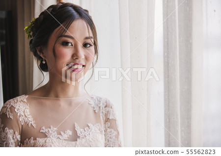 Asian bride standing near window in dressing 55562823