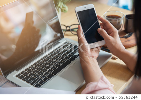 Beautiful young woman using phone and laptop in 55563244
