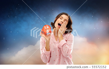 sleepy woman in pajama with alarm clock yawning sleepy woman in pajama with alarm clock yawning 55572152