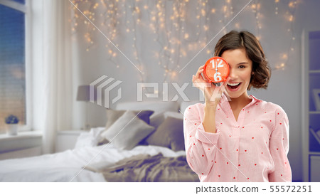 happy young woman in pajama with alarm clock 55572251