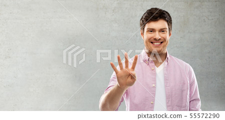 man showing four fingers over grey concrete wall 55572290