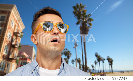 surprised man in sunglasses over venice beach 55572421