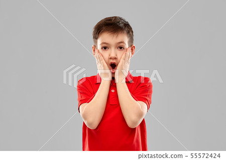 shocked little boy in red t-shirt touching face 55572424