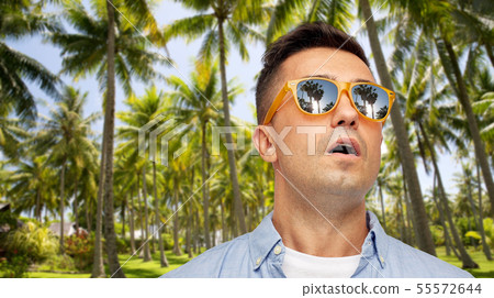 surprised man in sunglasses over tropical beach 55572644
