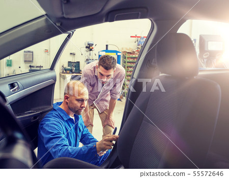 mechanic and man checking seat belt at car shop mechanic and man checking seat belt at car shop 55572646