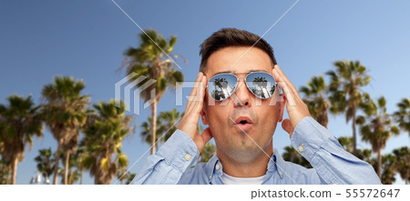 surprised man in sunglasses over palm trees surprised man in sunglasses over palm trees 55572647