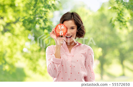 happy young woman in pajama with alarm clock 55572650