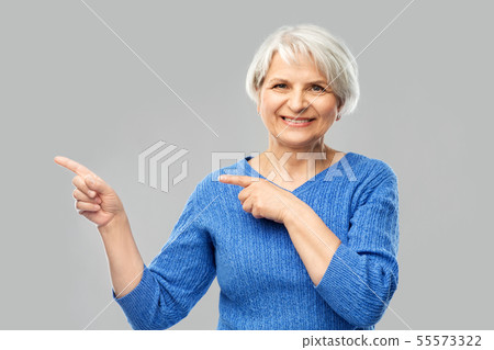 smiling senior woman pointing fingers to something 55573322