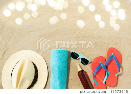 straw hat, flip flops and sunglasses on beach sand 55573346