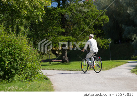 happy senior man riding bicycle at summer park happy senior man riding bicycle at summer park 55573835