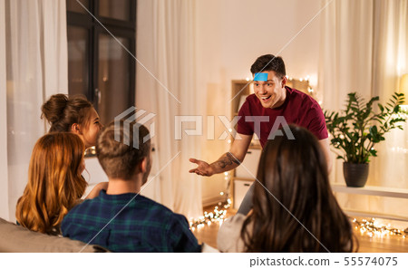 friends playing guessing game at home in evening 55574075