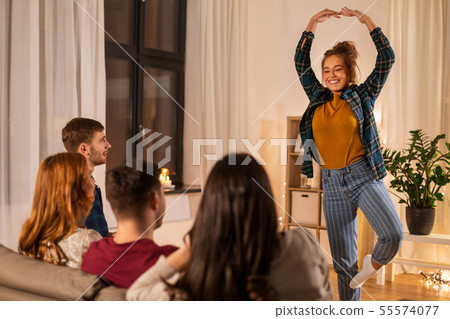 happy friends playing charades at home in evening 55574077