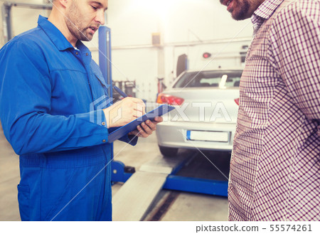 auto mechanic with clipboard and man at car shop auto mechanic with clipboard and man at car shop 55574261