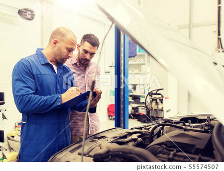 auto mechanic with clipboard and man at car shop 55574507