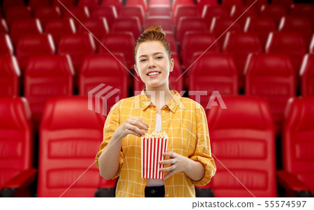redhead teenage girl with popcorn at movie theater 55574597