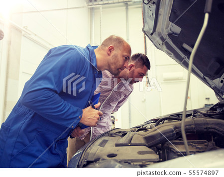 auto mechanic with clipboard and man at car shop 55574897