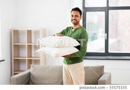 happy indian man holding pillows at home 55575335