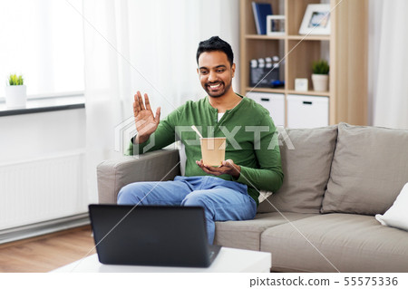 man having video call on laptop and eating at home man having video call on laptop and eating at home 55575336