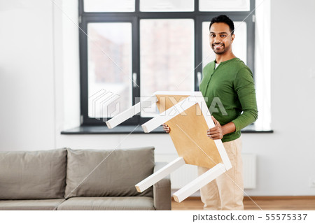 happy indian man holding coffee table at home happy indian man holding coffee table at home 55575337