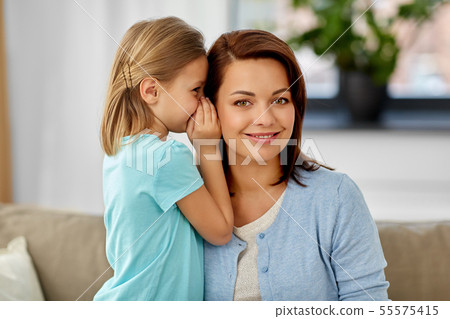 daughter whispering secret to mother at home 55575415
