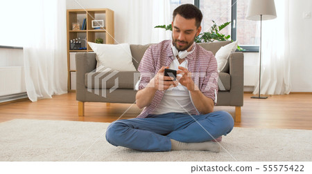smiling man using smartphone at home smiling man using smartphone at home 55575422