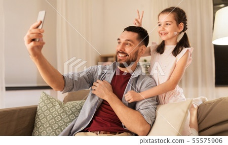 father and daughter taking selfie at home 55575906