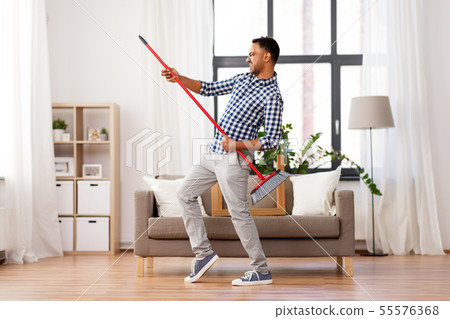 man with broom cleaning and having fun at home man with broom cleaning and having fun at home 55576368