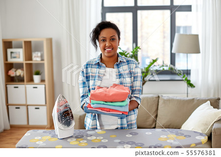 african american woman with ironed clothes at home 55576381