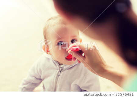 mother with spoon feeding little baby at home 55576481