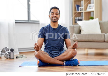 indian man meditating in lotus pose at home indian man meditating in lotus pose at home 55576793