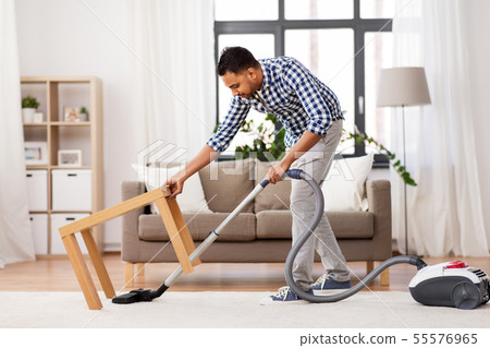 indian man with vacuum cleaner at home 55576965