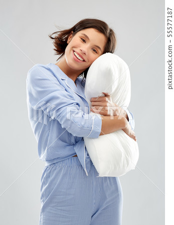 happy young woman in pajama hugging pillow 55577187