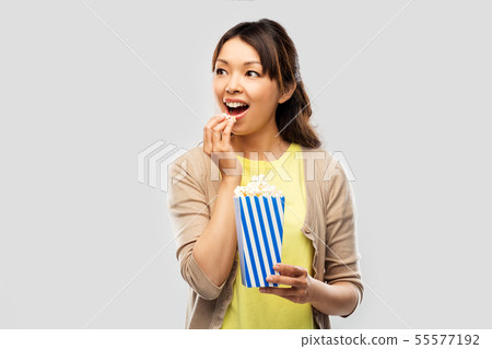 smiling asian woman eating popcorn smiling asian woman eating popcorn 55577192