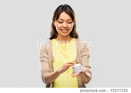 happy young asian woman holding jar of moisturizer happy young asian woman holding jar of moisturizer 55577193