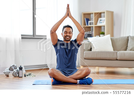 indian man meditating in lotus pose at home 55577216