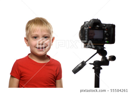 Smiling blond boy in front of the camera lens. Smiling blond boy in front of the camera lens. 55584261